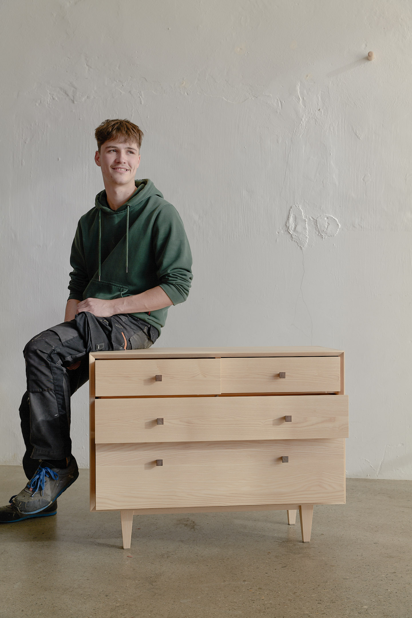 junger Mann sitzt auf Sideboard