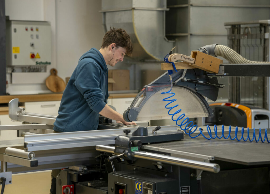 Mann steht an einer großen Kreissäge