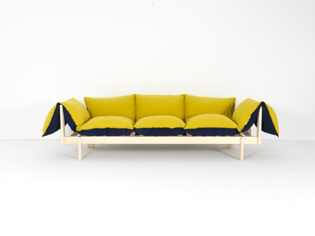 Sofa Sofa mit gelben und schwarzen Kissen auf Ahornholzgestell vor weißer Wand.