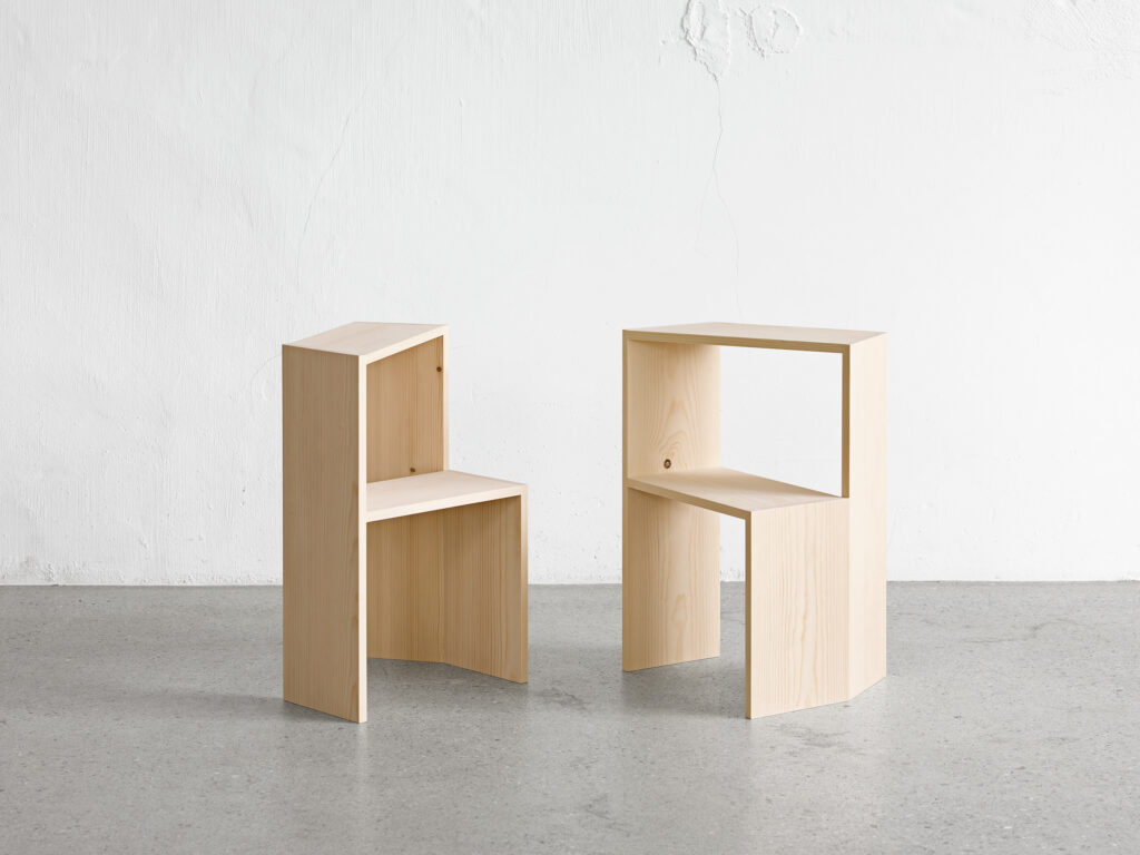 Zwei Holzstufenhocker in Weißtanne stehen auf Betonboden vor einer weißen Wand.