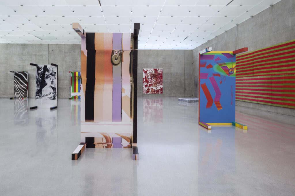 Tische bedruckt mit geometrischen und gestreiften Mustern in einem modernen Ausstellungsraum mit Betonwänden.